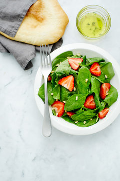 Salad served with spinach, strawberry and pine nuts