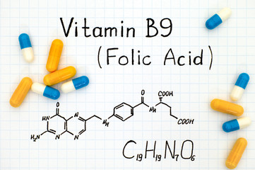 Chemical formula of Vitamin B9 (Folic Acid) with pills.