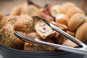 variety of bread buns and a metal tongs. 