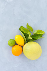 oranges, lime, lemon with green leaves on a gray texture background top view. still life with citrus on a dark background.
