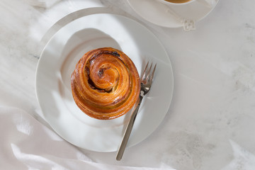 French fancy rolls of snails with raisins and a cup of coffee top view. image of food with sunlight of dawn, shadows and highlights