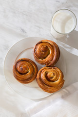 French fancy rolls of snails with raisins and a glass of milk from above. image of food with sunlight of dawn, shadows and highlights