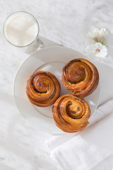 French fancy rolls of snails with raisins and a glass of milk from above. image of food with sunlight of dawn, shadows and highlights