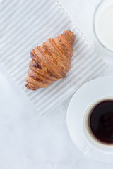 French croissant with coffee and a glass of milk on the table top view. European breakfast