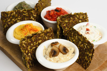Appetizer of hummus, guacamole, veggie salsa, creamy cheese with sundried tomatoes and julienne with mushrooms with bread on a wooden desk isolated on white background