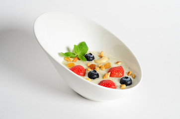 Oat porridge with berries and nuts in a bowl isolated on white background