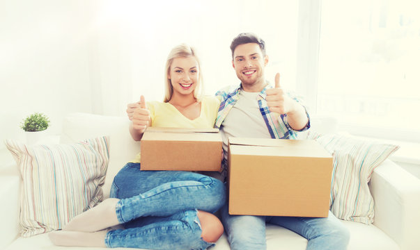 happy couple with boxes showing thumbs up at home