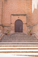 landmark of stairs and ancient wooden door of church San Mateo, from Fifteenth century, in Banos de la Encina, Jaen, Andalusia, Spain Europe
