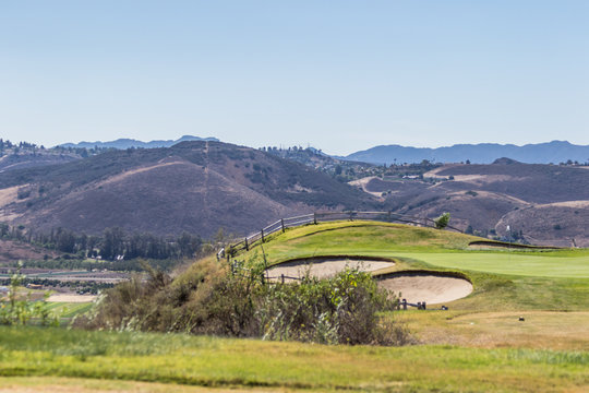 Picturesque green golf field with a wooden fence
