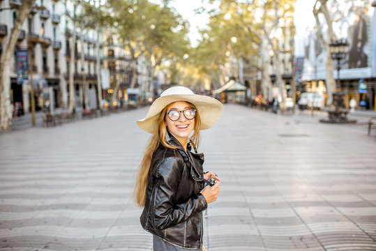 Young woman tourist in hat walking on the famous pedestrian boulevard in Barcelona city
