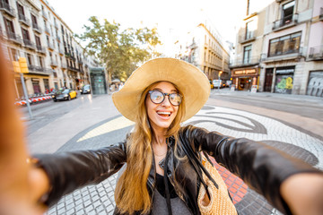 Obraz premium Young woman tourist making selfie photo standing on the central street with famous colorful tiles in Barcelona city