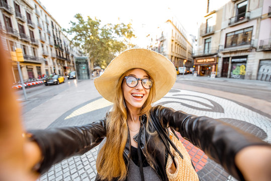 Young woman tourist making selfie photo standing on the central street with famous colorful tiles in Barcelona city