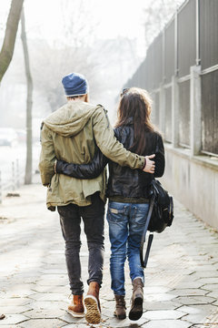 Young couple walking on the street - back view
