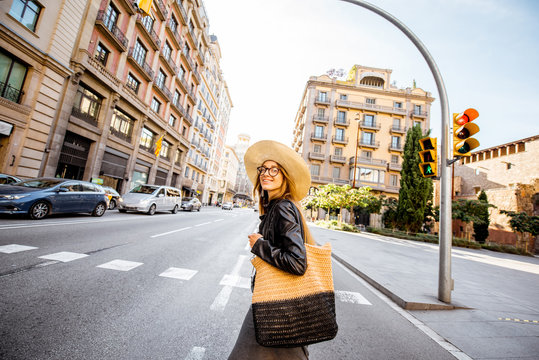 Woman tourist in hat crossing the street during the morning light in Barcelona city