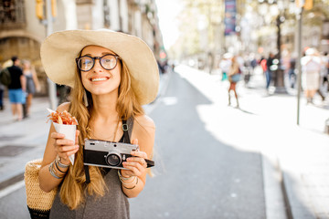 Fototapeta premium Young woman tourist holding jamon walking outdoors on the street in Barcelona city