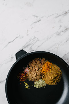ground spices in a frypan on a marble background