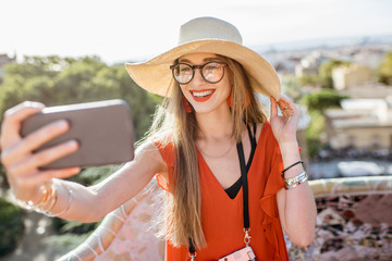 Fototapeta premium Portrait of a young woman tourist in red dress having fun visiting famous Guell park in Barcelona