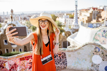 Obraz premium Portret młodej kobiety turystki w czerwonej sukience podczas wizyty w słynnym parku Guell w Barcelonie