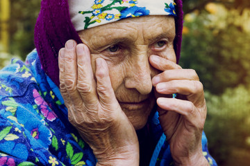 An old grandmother wipes a tear from her eyes