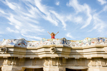 Fototapeta premium View on the beautiful terrace decorated with mosaic with happy woman tourist in Guell park in Barcelona. Wide angle view with copy space
