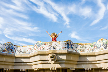 Fototapeta premium View on the beautiful terrace decorated with mosaic with happy woman tourist in Guell park in Barcelona. Wide angle view with copy space