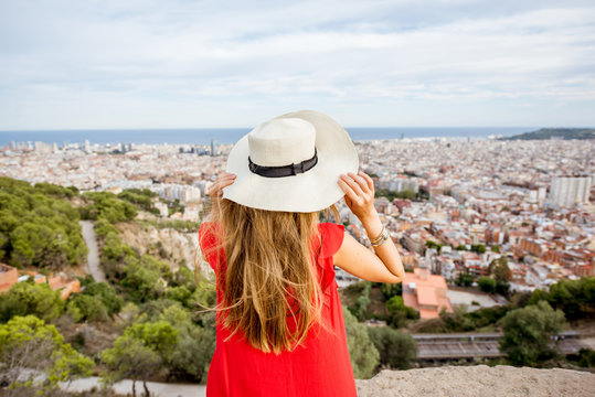Young woman tourist in hat enjoying great cityscape view on Barcelona