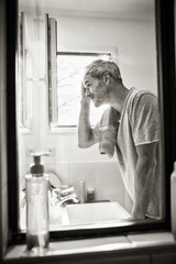  Handsome gray haired man examining his hair in the bathroom