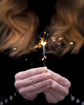 Close-up of woman hand holding a heart shaped sparkler