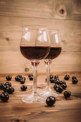 Two glasses of red wine and grapes on wooden table