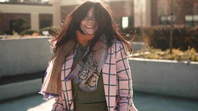 portrait of a cute young woman at sunset. a beautiful girl walks through the city and playfully posing on camera. slow motion