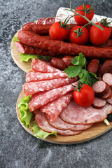 Food tray with delicious salami, pieces of sliced ham, sausage, tomatoes, salad and vegetable - Meat platter with selection - Cutting sausage and cured meat