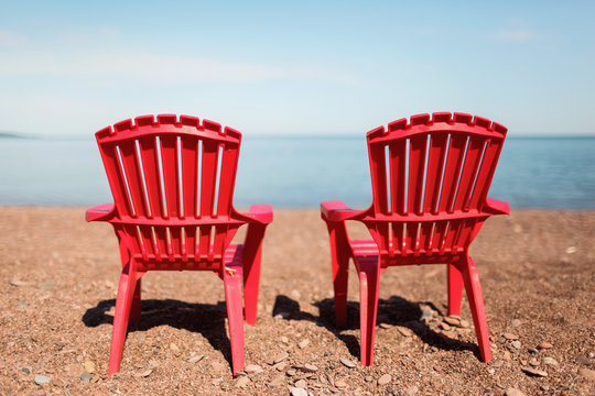 two red, empty chairs in front of lake superior