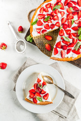 Homemade biscuit cake with whipped cream, fresh organic raw strawberries and mint. On a white stone table. Copy space top view