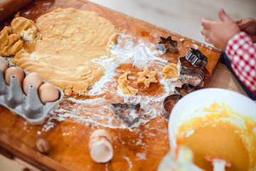 Happy little child, cute kid girl at the table in domestic kitchen making gingerbread xmas cookies decorated for Christmas holiday. Girl helping and having fun