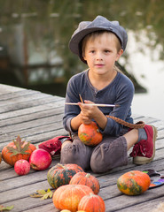 Fototapeta premium Cheerful boy sitting with Halloween pumpkins