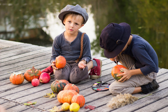 Friendly children paint small Halloween pumpkins