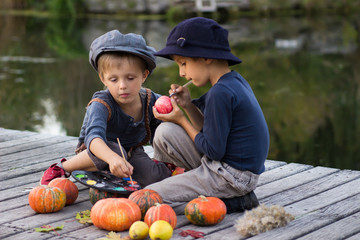 Two smiling boys paint small apples