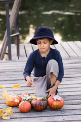 Fototapeta premium Smiling boy sitting with pumpkins
