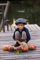 Fototapeta premium Little boy sitting with pumpkins