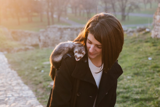 Young woman with a pet ferret in the park