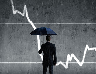 Businessman with umbrella standing over column diagram background. Business, crisis, default concept.