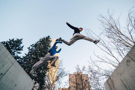 Two men jumping during a parkour training at sunset