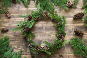 Christmas wreath with fir branches and pine cone on wooden tabletop. Flat lay.