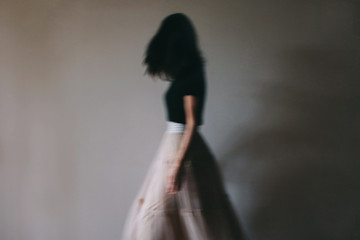Old fashioned, moody looking, image of woman moving in a long, full, skirt