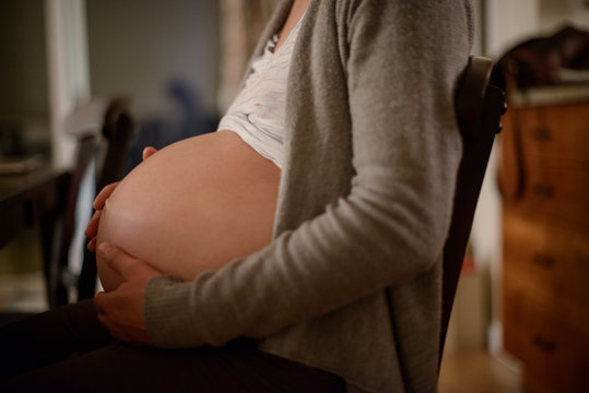 Pregnant woman holds belly nearing end of term.