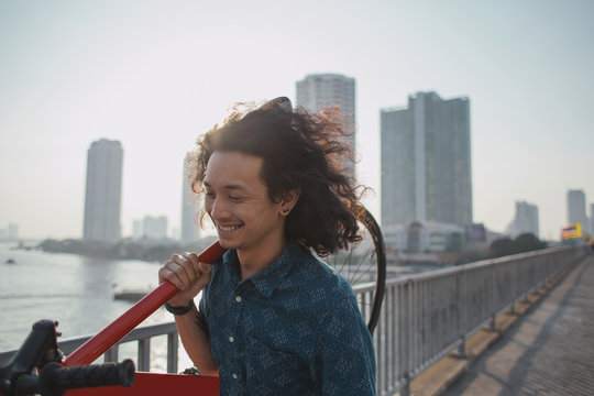 Young Asian man holding his bike and smiling