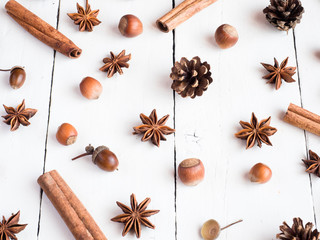 Cinnamon sticks spice star fir cones on white wooden background Flat lay