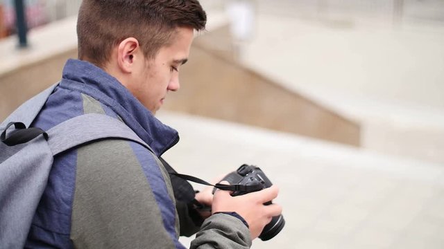 Young guy looks at the digital camera while in the city