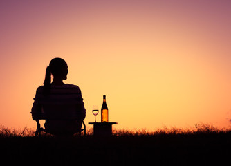 Thoughtful woman enjoying wine and a sunset view. 