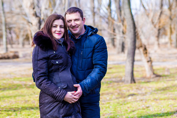 Fototapeta premium Beautiful pregnant woman and her handsome husband hugging the tummy